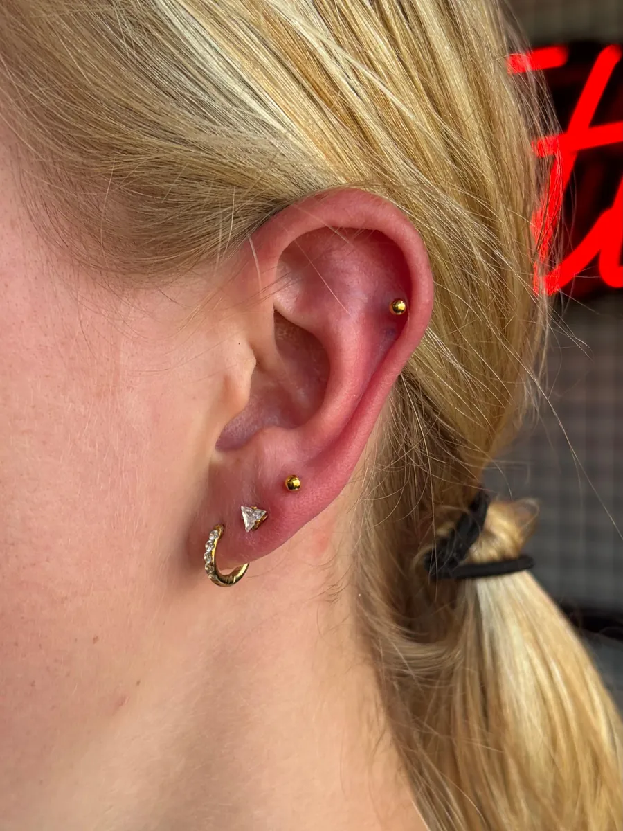 Kulağın üst dış kıvrımında helix piercing, altında lob piercingleri